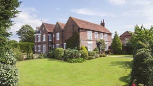 A large, two-story house with a well-maintained lawn and mature trees. - The Newtown House Hotel (Hayling Island)