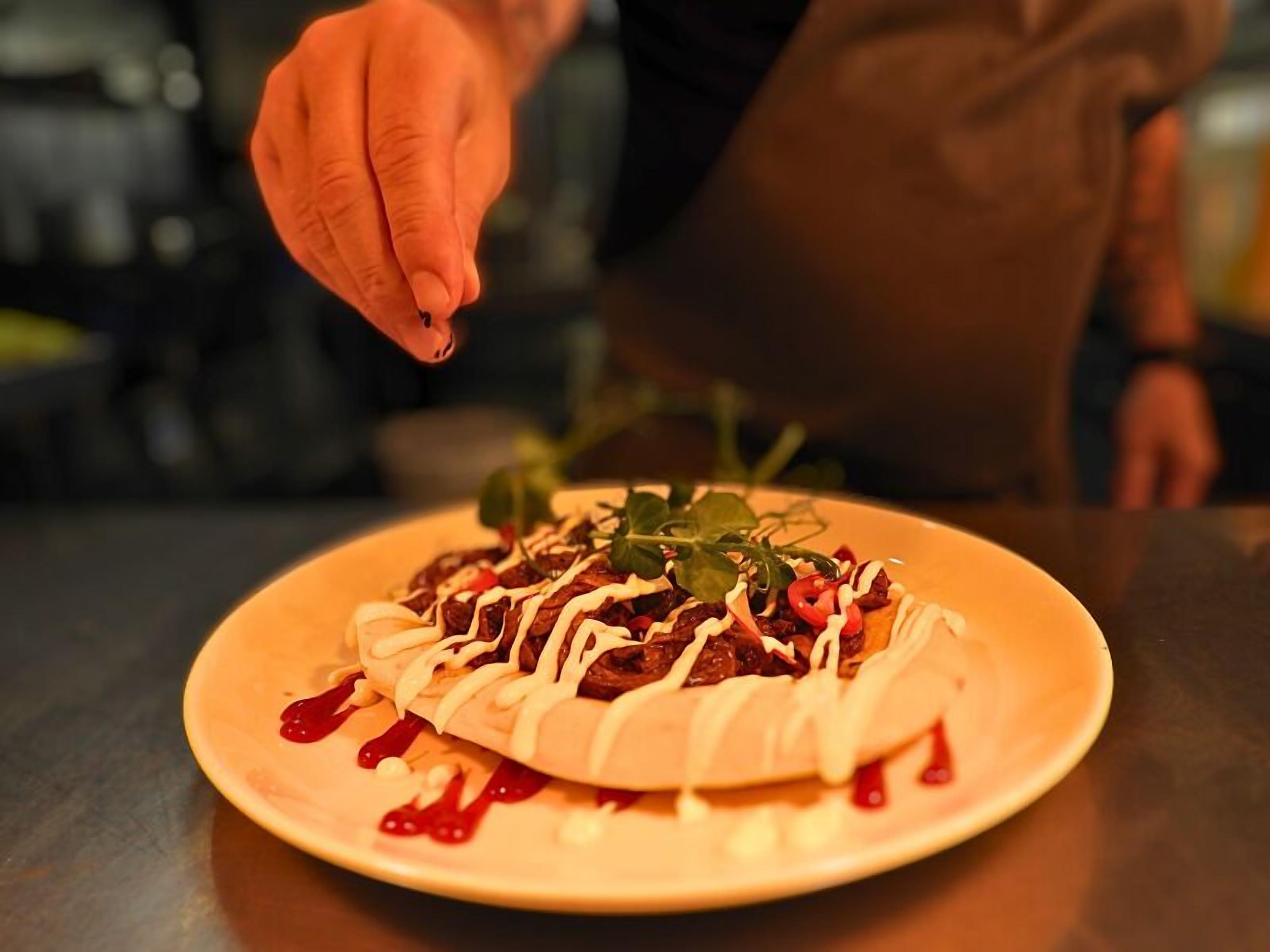Una persona decorando un plato con salsa.