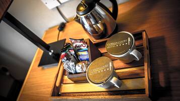 A wooden tray with a tea kettle, two mugs, and a box of tea bags on a wooden table.