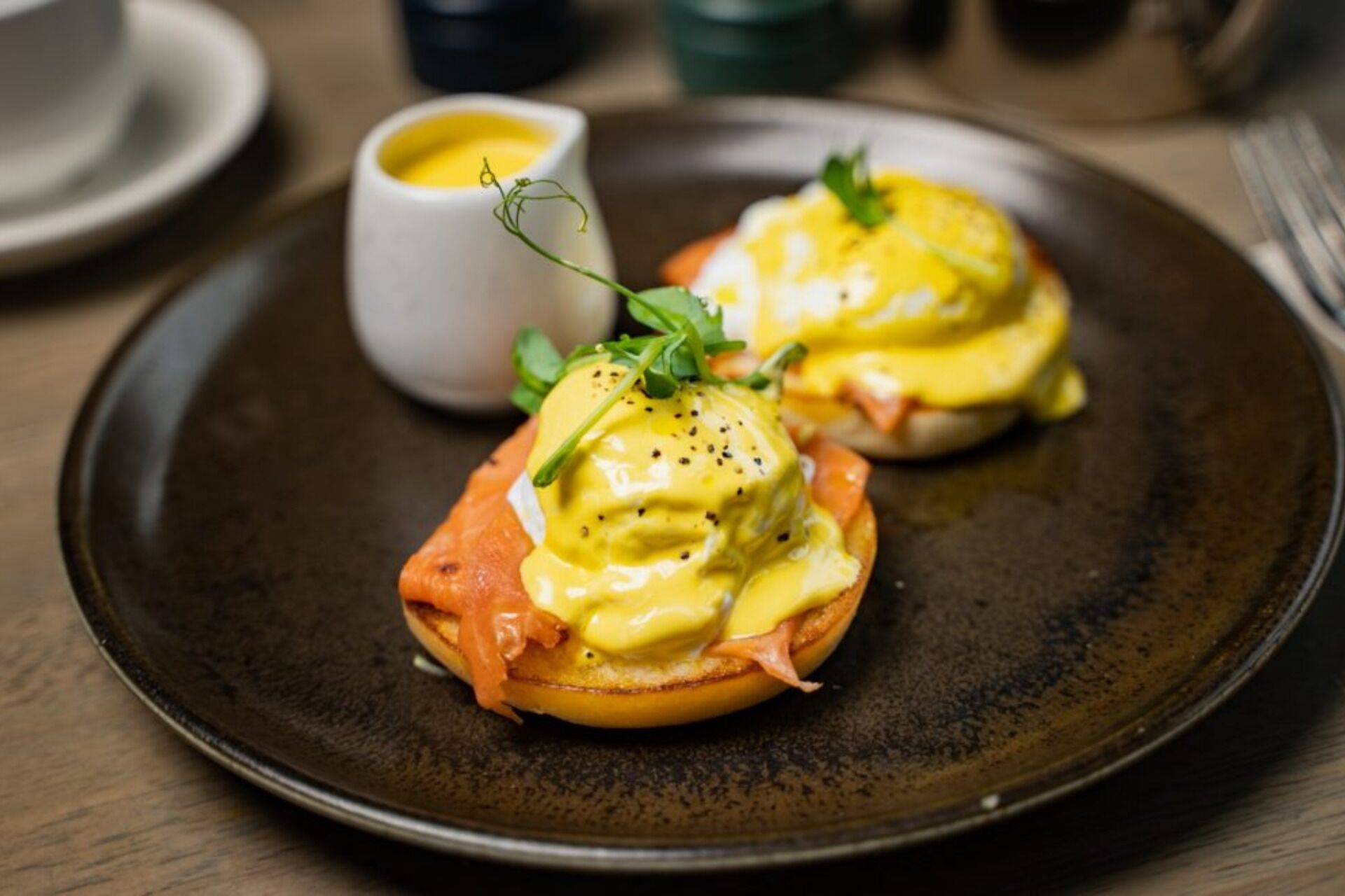 A plate with two eggs benedict sandwiches garnished with herbs.