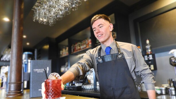 A bartender at a CURRAN COURT HOTEL bar, holding a drink with a lemon slice. - Curran Court Hotel (Larne)