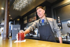 Ein Barkeeper in der Bar des CURRAN COURT HOTEL hält ein Getränk mit einer Zitronenscheibe.