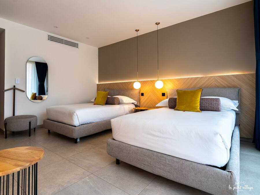 A modern hotel room with two beds, a round table, and a mirror.