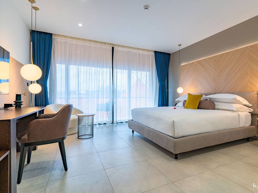 Una habitación de hotel moderna con una cama grande, un escritorio y una silla.