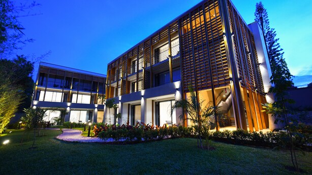 A modern hotel with a two-story structure, large windows, and a well-lit entrance. - Le Petit Village Hotel & Spa (Kampala)