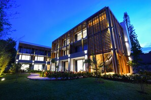 A modern hotel with a two-story structure, large windows, and a well-lit entrance. - Le Petit Village Hotel & Spa (Kampala)