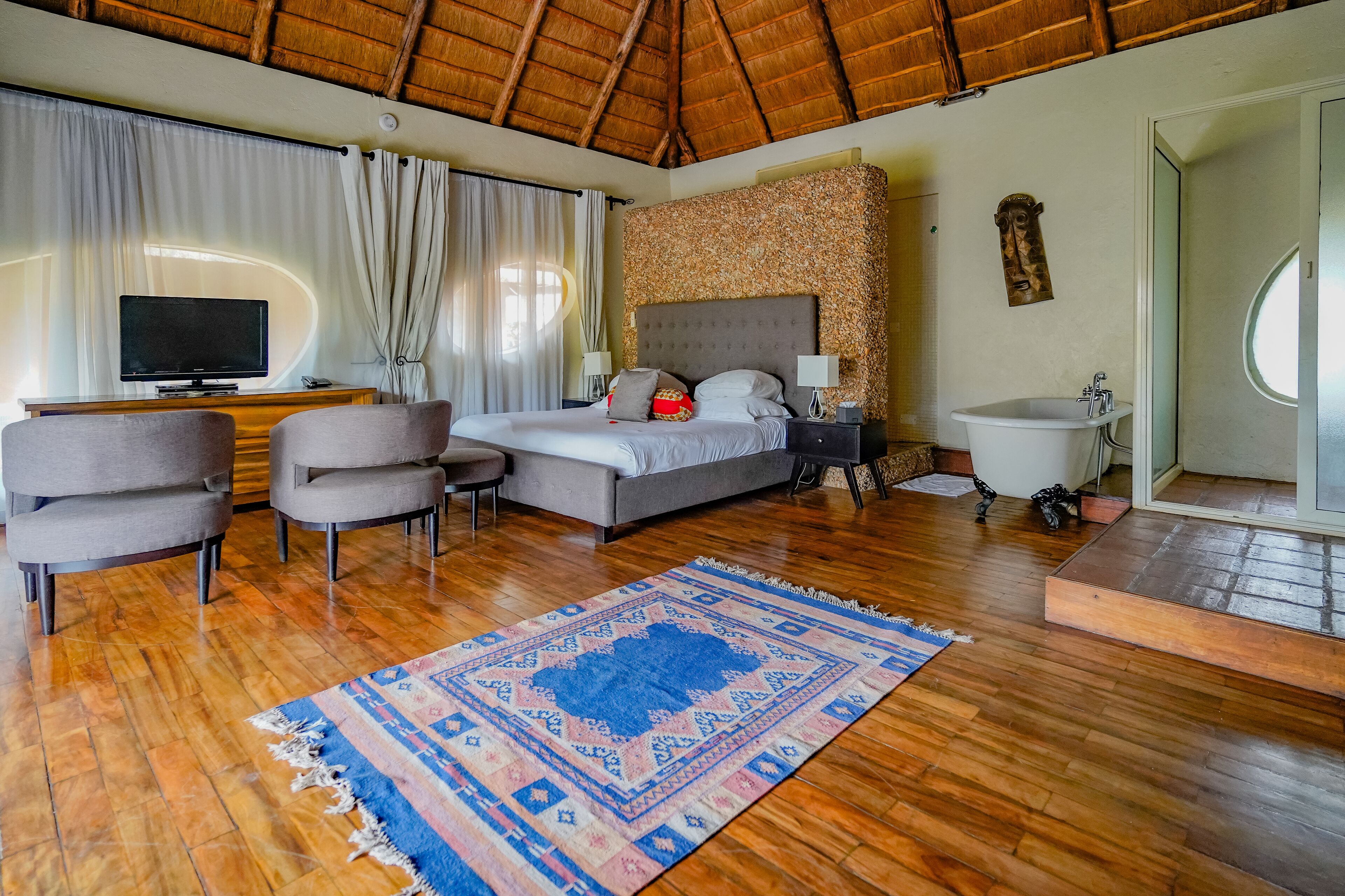 A bedroom with a bed, a TV, a desk, and a bathroom.