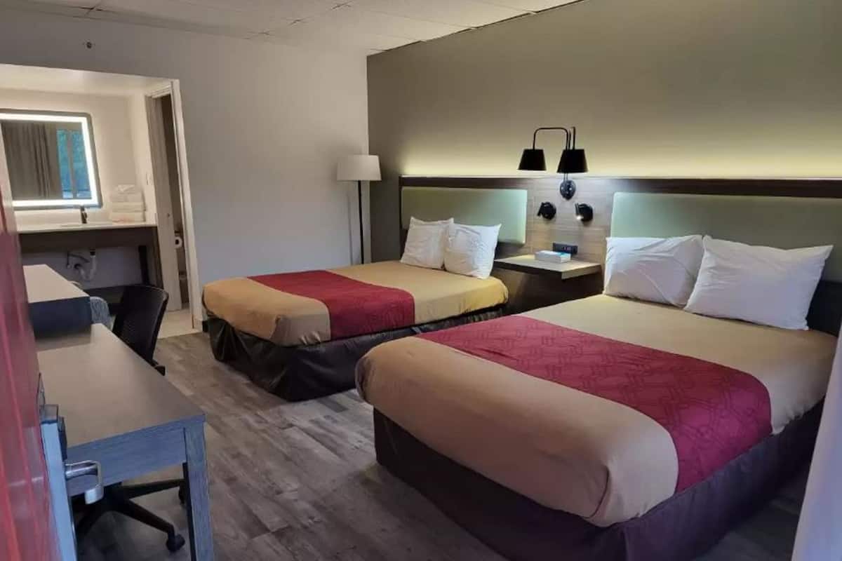 A hotel room with two beds, a desk, and a chair.