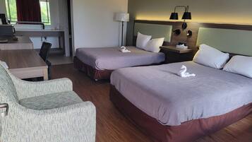 Una habitació d'hotel amb dos llits, un escriptori, una cadira i una làmpada.