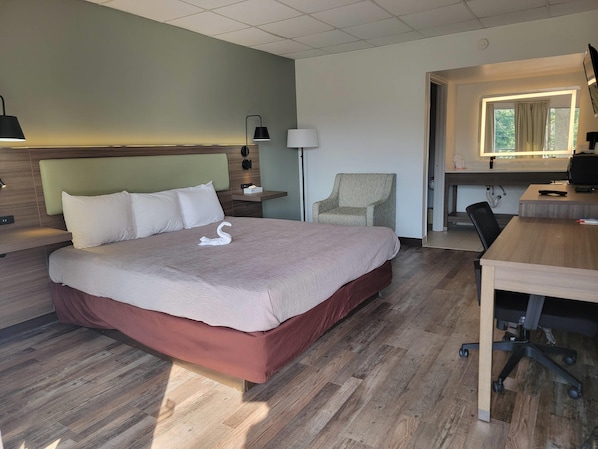 Une chambre d’hôtel comprenant un lit, une table de chevet, une lampe, une chaise, un bureau et une vue sur l’extérieur.