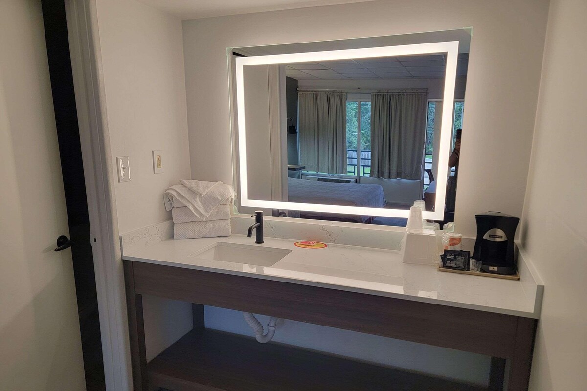 A modern bathroom with a large mirror, a sink, and a coffee machine.