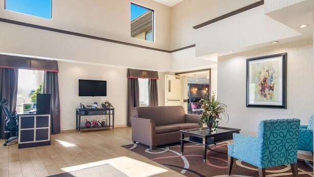 Een ruime woonkamer met een bank, fauteuil, salontafel, een flatscreen televisie en een klein tv-meubel.