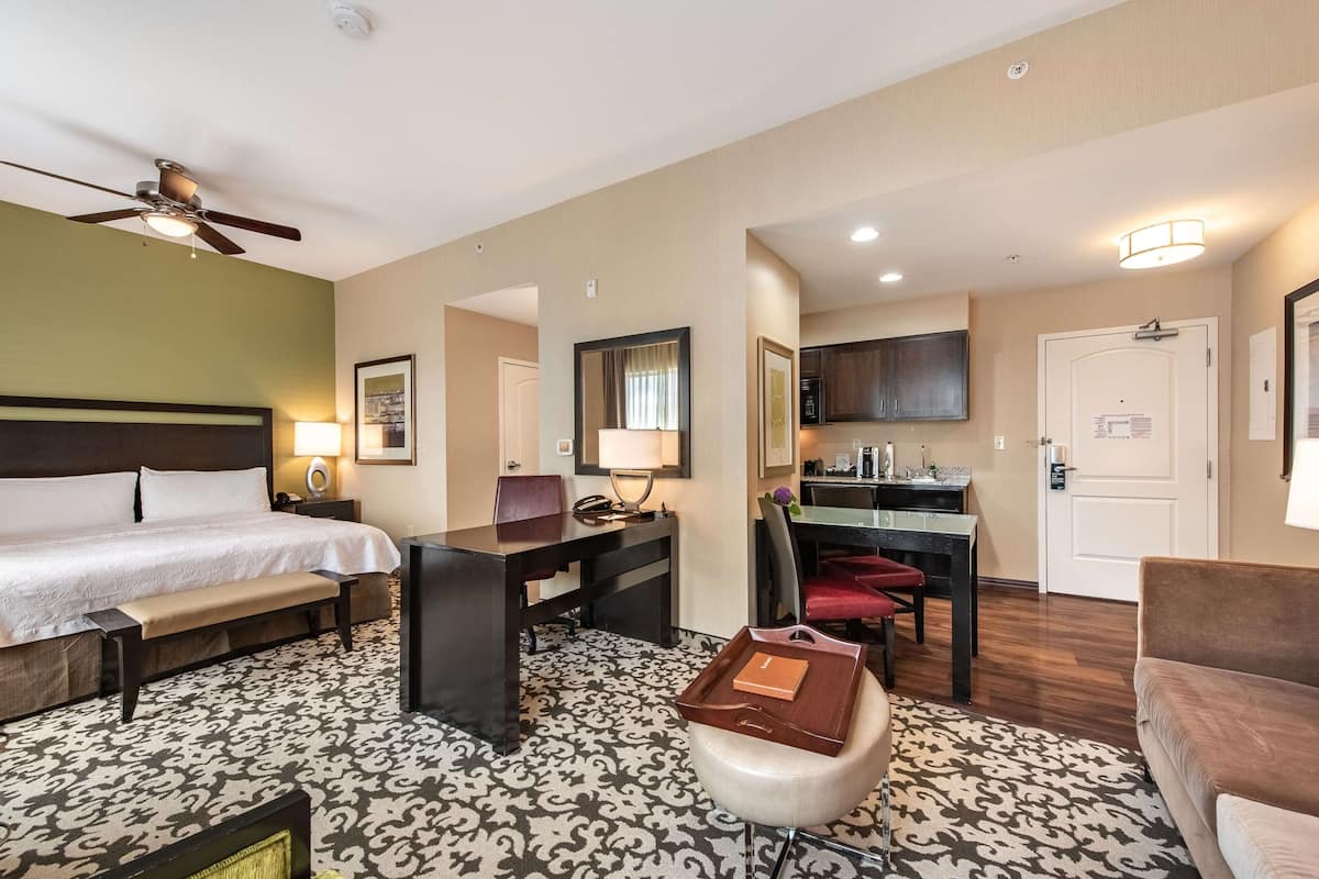 Ein Hotelzimmer mit Bett, Schreibtisch, Stuhl und einer kleinen Sitzecke.