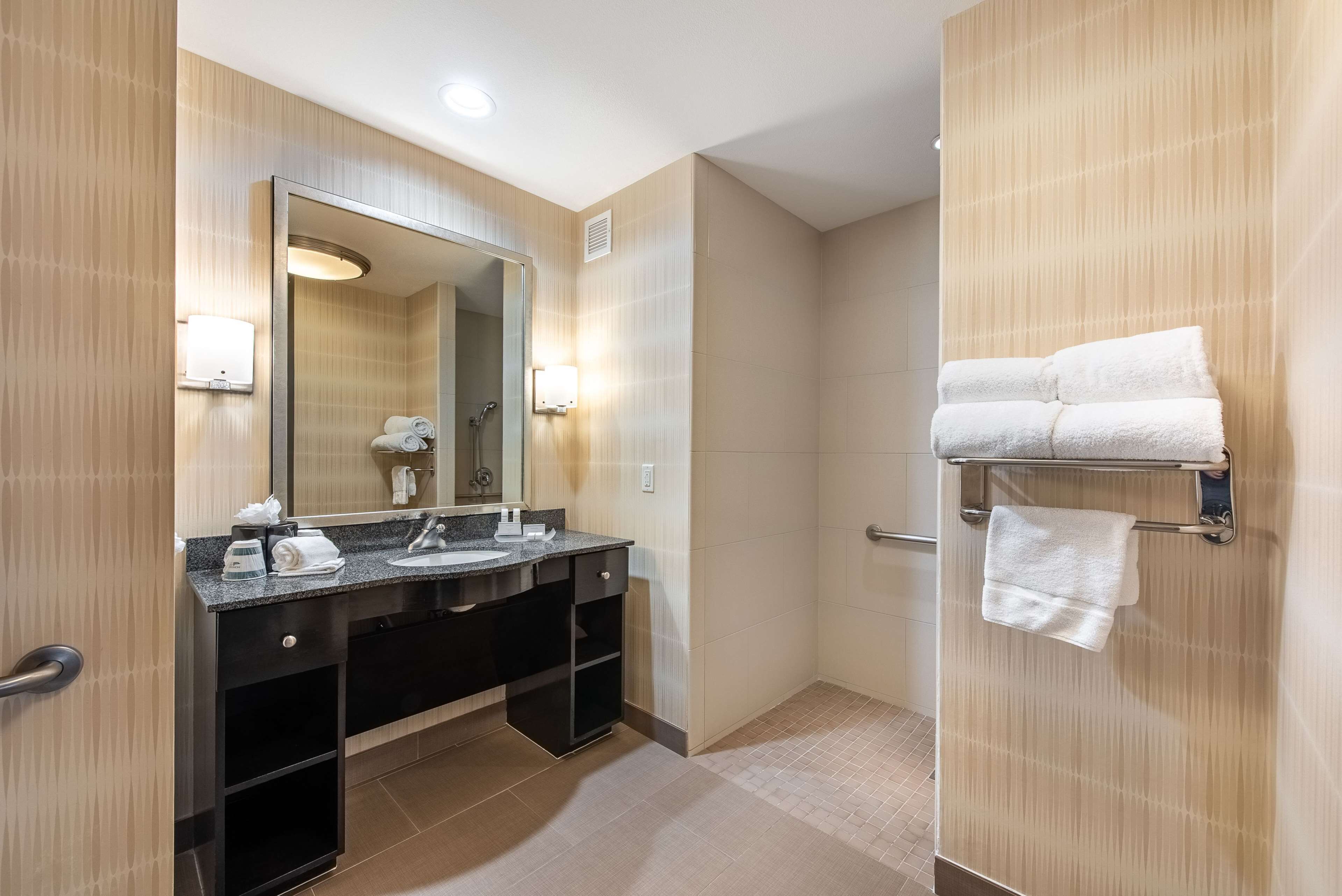 Une salle de bain moderne dotée d’un grand miroir, de deux vasques, d’un porte-serviettes et d’un espace douche.