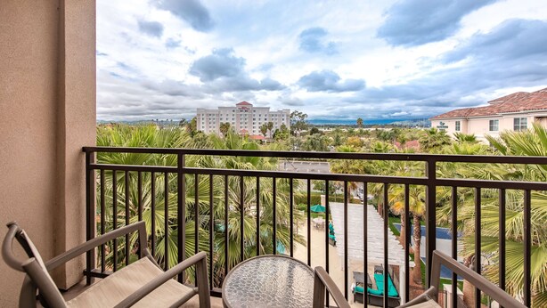 A balcony with a view of a hotel, palm trees, and a cloudy sky. - Homewood Suites by Hilton Oxnard/Camarillo (Oxnard)