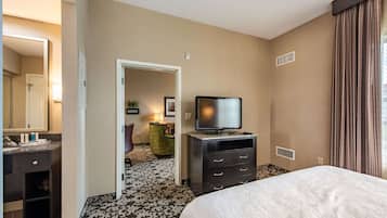 A hotel room with a bed, a television on a dresser, a mirror, and a door leading to another room.
