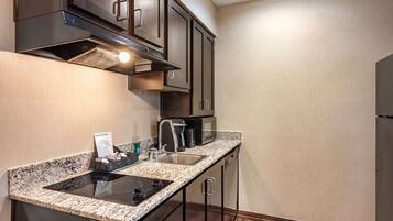 A modern kitchen with dark wood cabinets, a granite countertop, a built-in microwave, and a stainless steel sink.