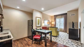 Une chambre d’hôtel équipée d’une kitchenette, d’un coin repas avec une table et des chaises, d’un canapé, d’une télévision et d’un tapis à motifs.
