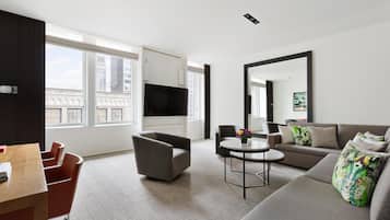 Uma sala de estar moderna com um sofá, poltronas, uma mesa de centro e uma televisão.