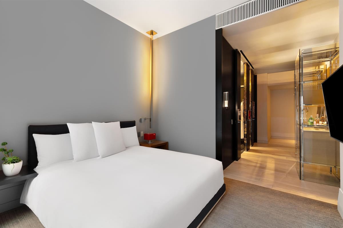 Una habitació d'hotel moderna amb un llit gran, una taula de nit i una petita planta en test.