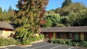 A motel with a parking lot, surrounded by trees and greenery. - Humboldt Redwoods Inn (Garberville)
