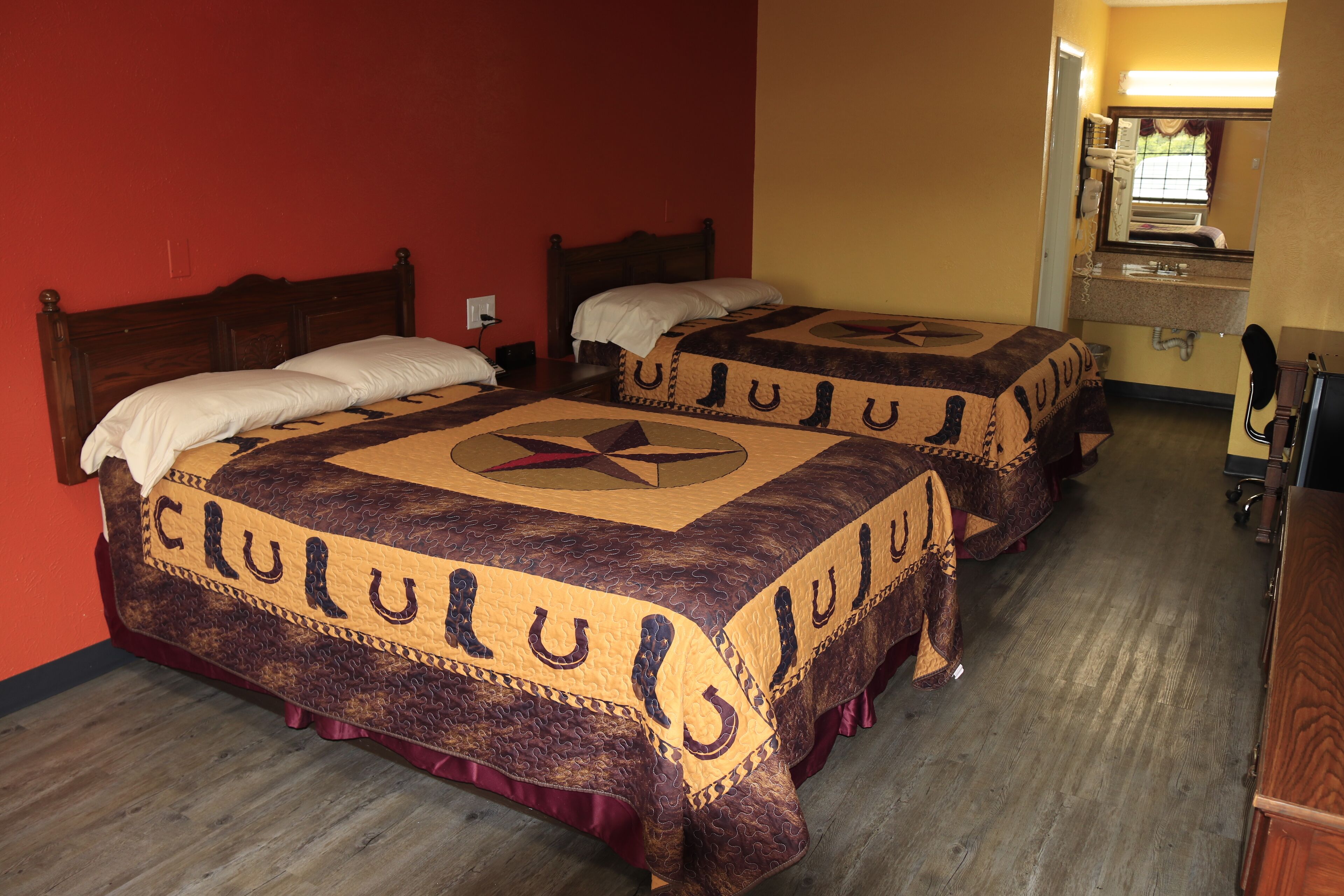 A hotel room with two beds, each with a unique patterned bedspread and a headboard.
