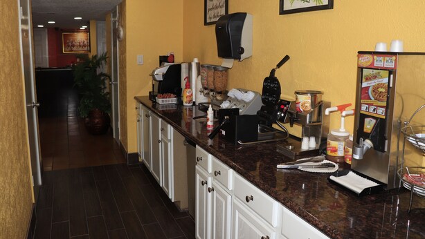 A kitchen with a coffee machine, condiment dispensers, and a refrigerator. - Chaparral Motel (Hallettsville)