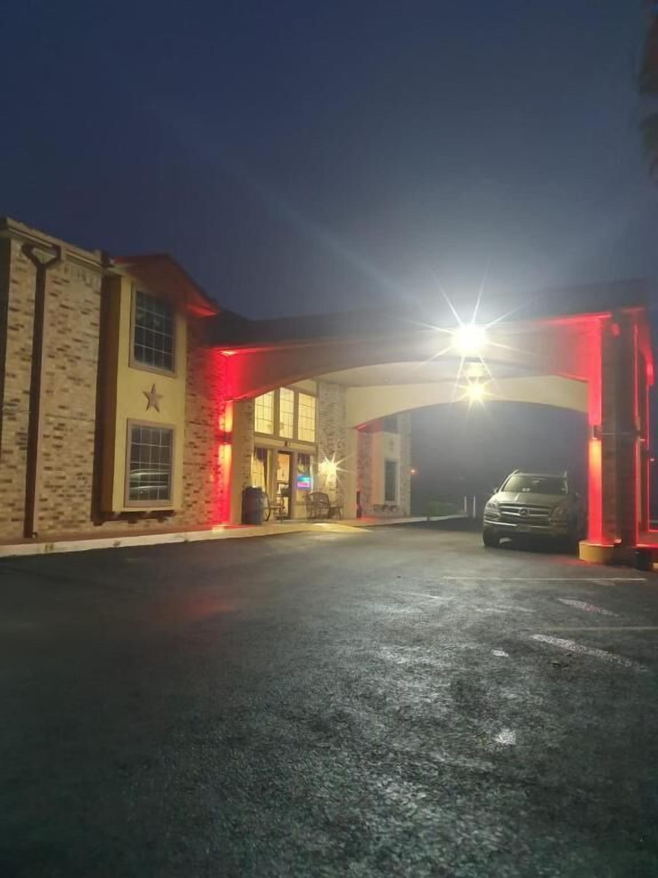 A building with a star on the facade, a car parked in front, and a bright light source above.