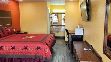 A hotel room with two beds, a desk, a chair, a TV, and a trash bin.