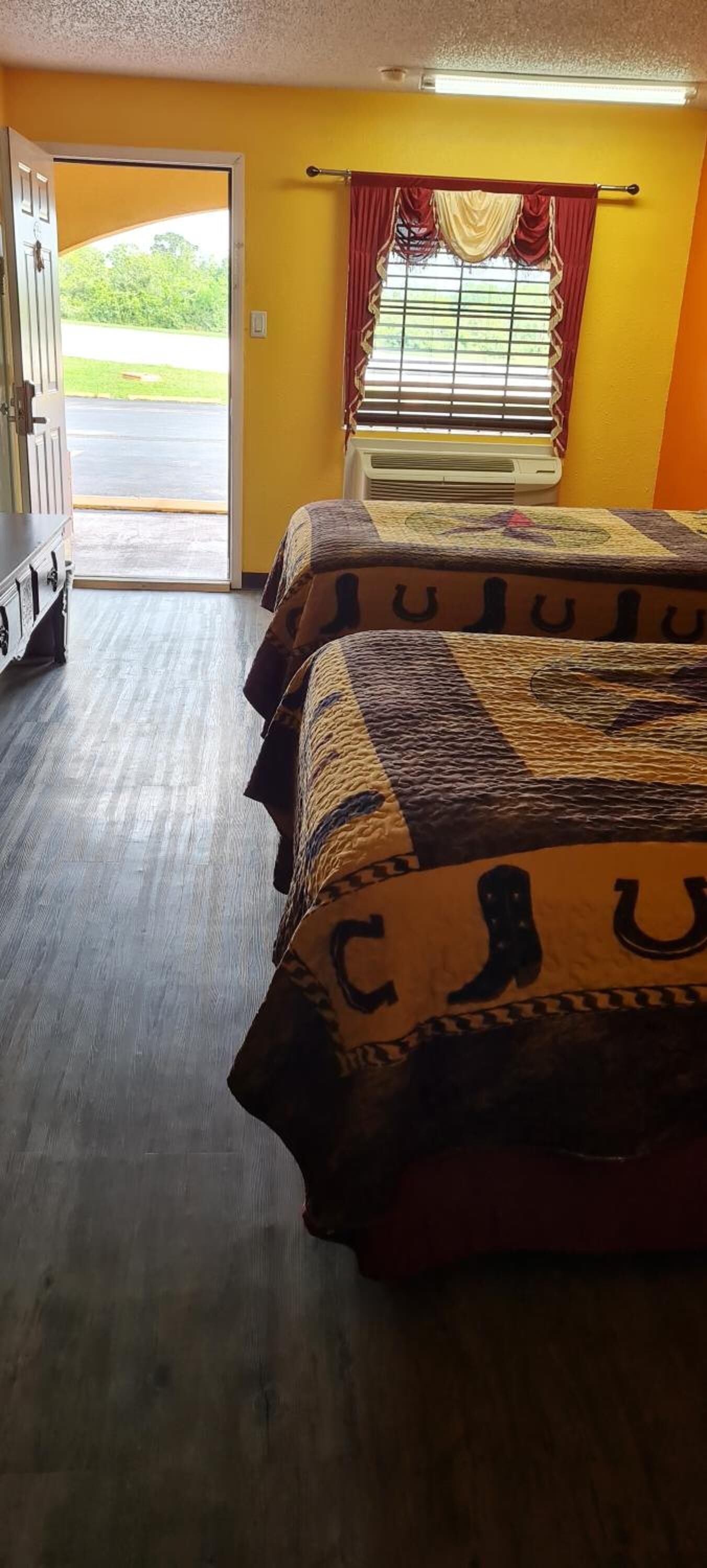 A room with a bed, a heater, a window with curtains, and a door leading outside.