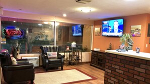A living room with a leather armchair, a small table, and a TV mounted on the wall. - Annie Oakley Motel Oakley (Oakley)