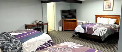 A hotel room with two beds, a desk, a chair, a television, and a framed picture on the wall.