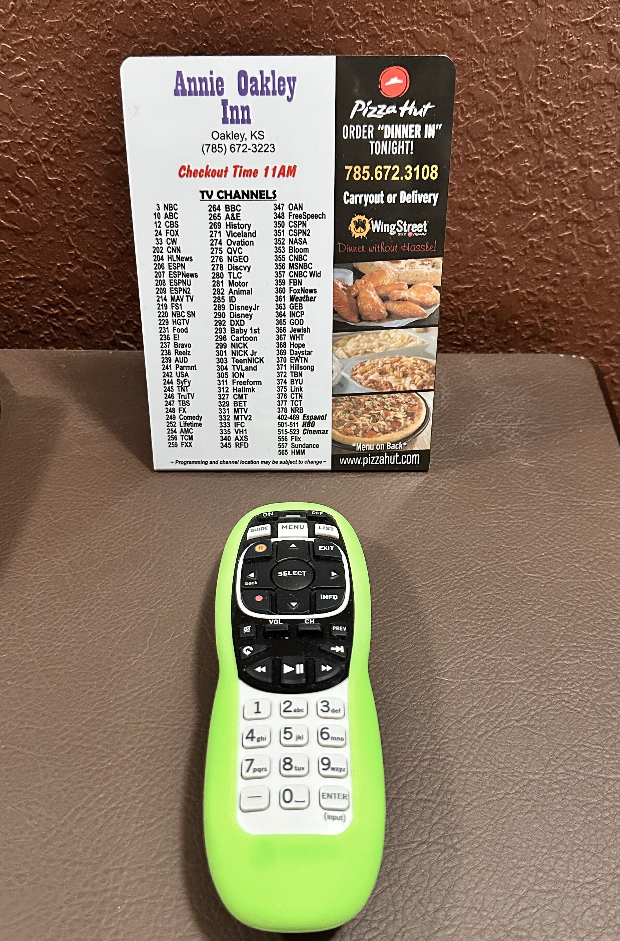 Un telecomando verde neon e una scatola di Pizza Hut su un tavolo.