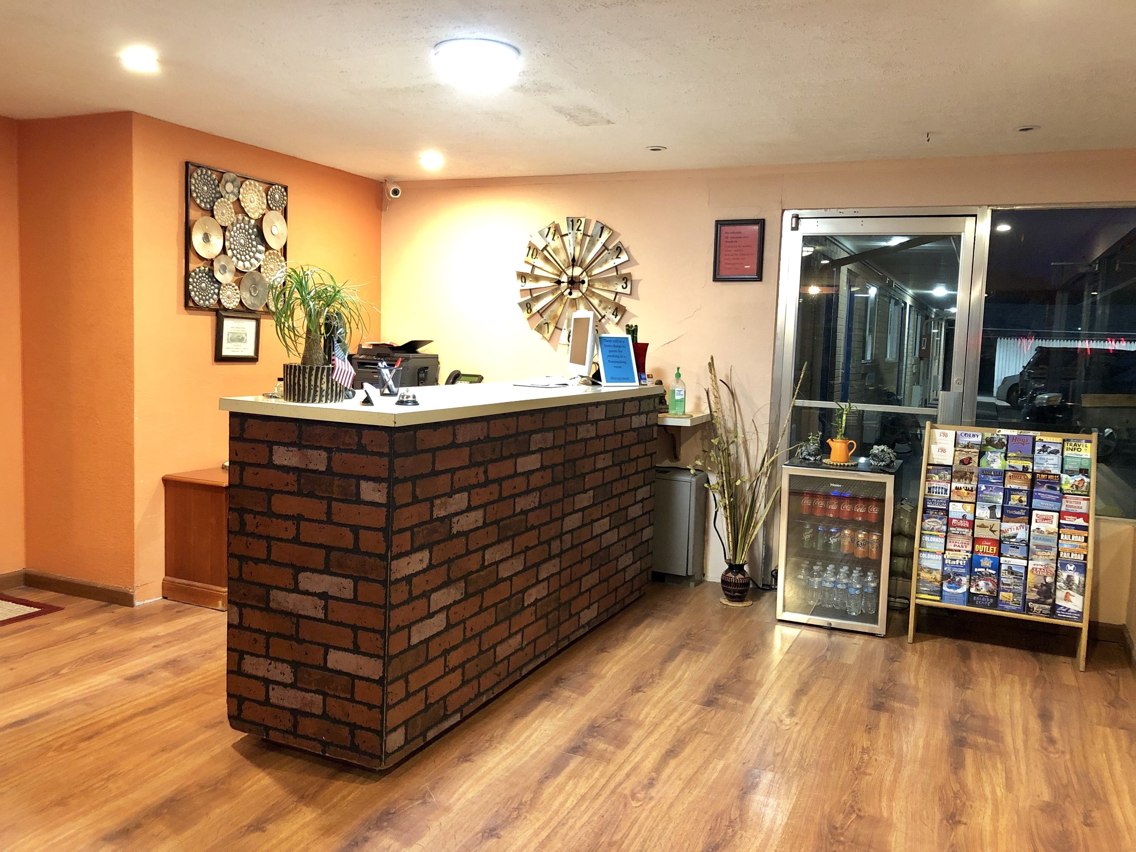 A reception area with a brick counter, a clock, a plant, and a travel information stand.