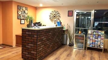 A reception area with a brick counter, a clock, a plant, and a travel information stand.