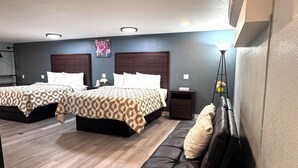 A hotel room with two beds, a sofa, a nightstand, and a floor lamp. - Annie Oakley Motel Oakley (Oakley)