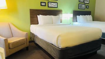 Una habitación de hotel con dos camas, una silla e imágenes enmarcadas en la pared.
