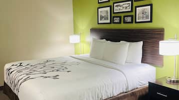 A hotel room with a bed, two bedside lamps, a nightstand, and a wall decorated with framed pictures.