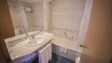A bathroom with a double sink, a bathtub, and a toilet.