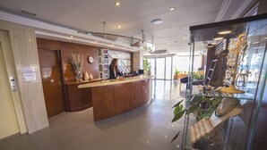 Zona d' recepció amb un taulell de fusta, un rellotge i una vitrina de vidre amb plantes.