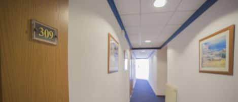A hallway with a blue carpet, wooden door labeled '309', and framed pictures on the walls.