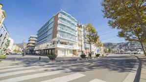 Un hotel de diversos pisos amb balcons, un pas de vianants i un cel serè.