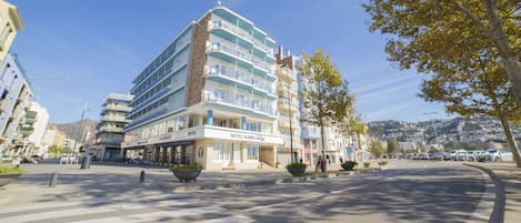 A multi-story hotel with balconies, a crosswalk, and a clear sky.