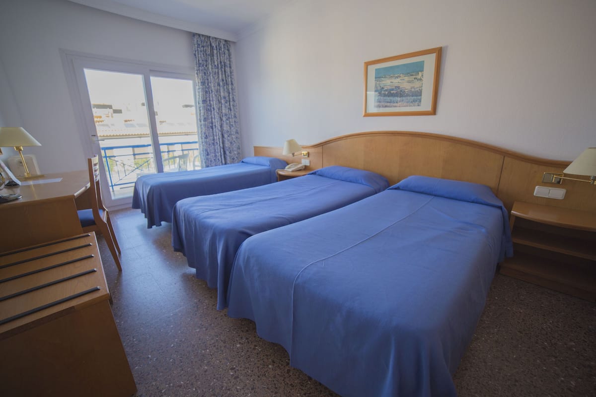 Habitación de hotel con dos camas, un escritorio, una silla, un teléfono y una ventana con vistas.