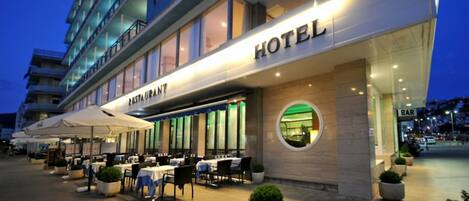 A hotel with a restaurant and bar area, outdoor seating, and a view of the cityscape.