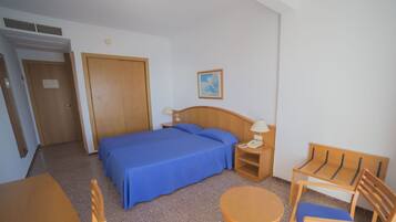 A hotel room with a bed, a desk, a chair, a nightstand, and a painting on the wall.