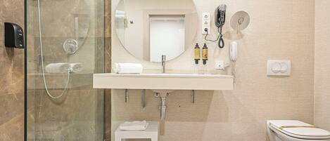 A modern bathroom with a glass-enclosed shower, a white sink with a mirror above it, and a toilet.
