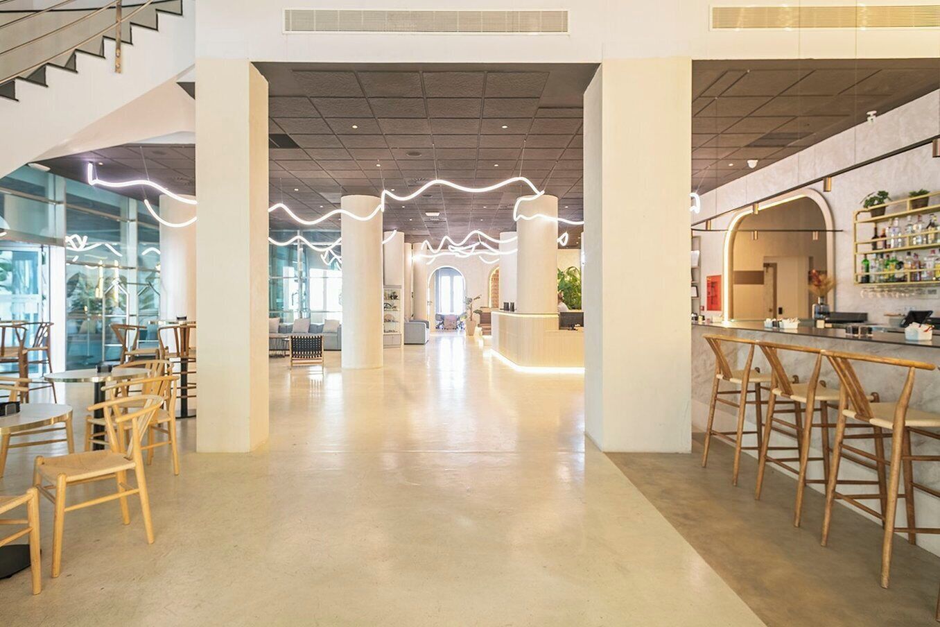 A spacious interior with a bar area, seating, and a staircase.