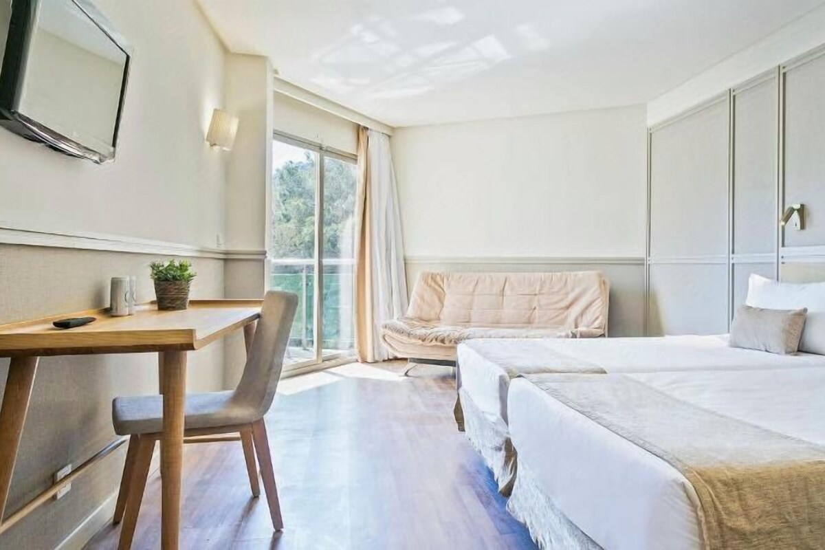 A hotel room with a bed, a desk, and a chair.