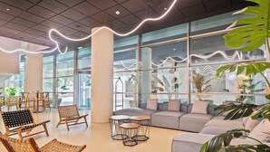 A spacious lobby with large windows, a grey sofa, wicker chairs, and a coffee table. - Cullera Holiday Hotel (Cullera)